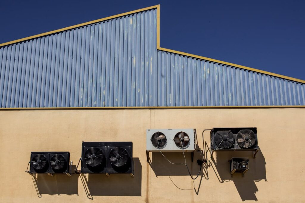PIC 1 Exterior view of industrial air conditioning units mounted on a warehouse wall under clear blue sky.
