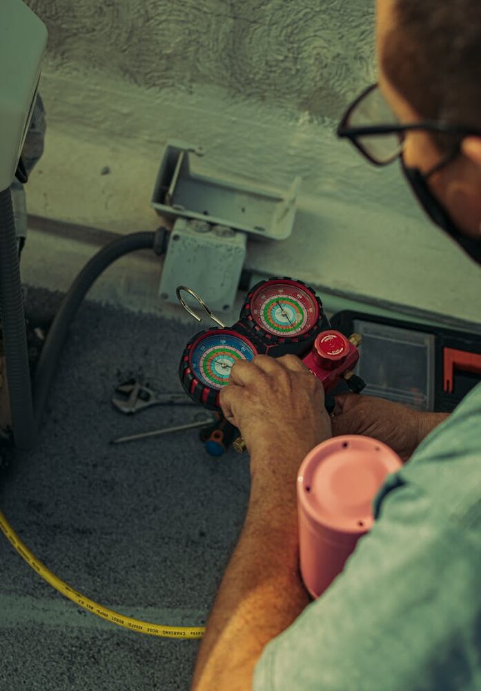 PIC 2 Professional technician adjusting a refrigerant manifold gauge for air conditioning maintenance.